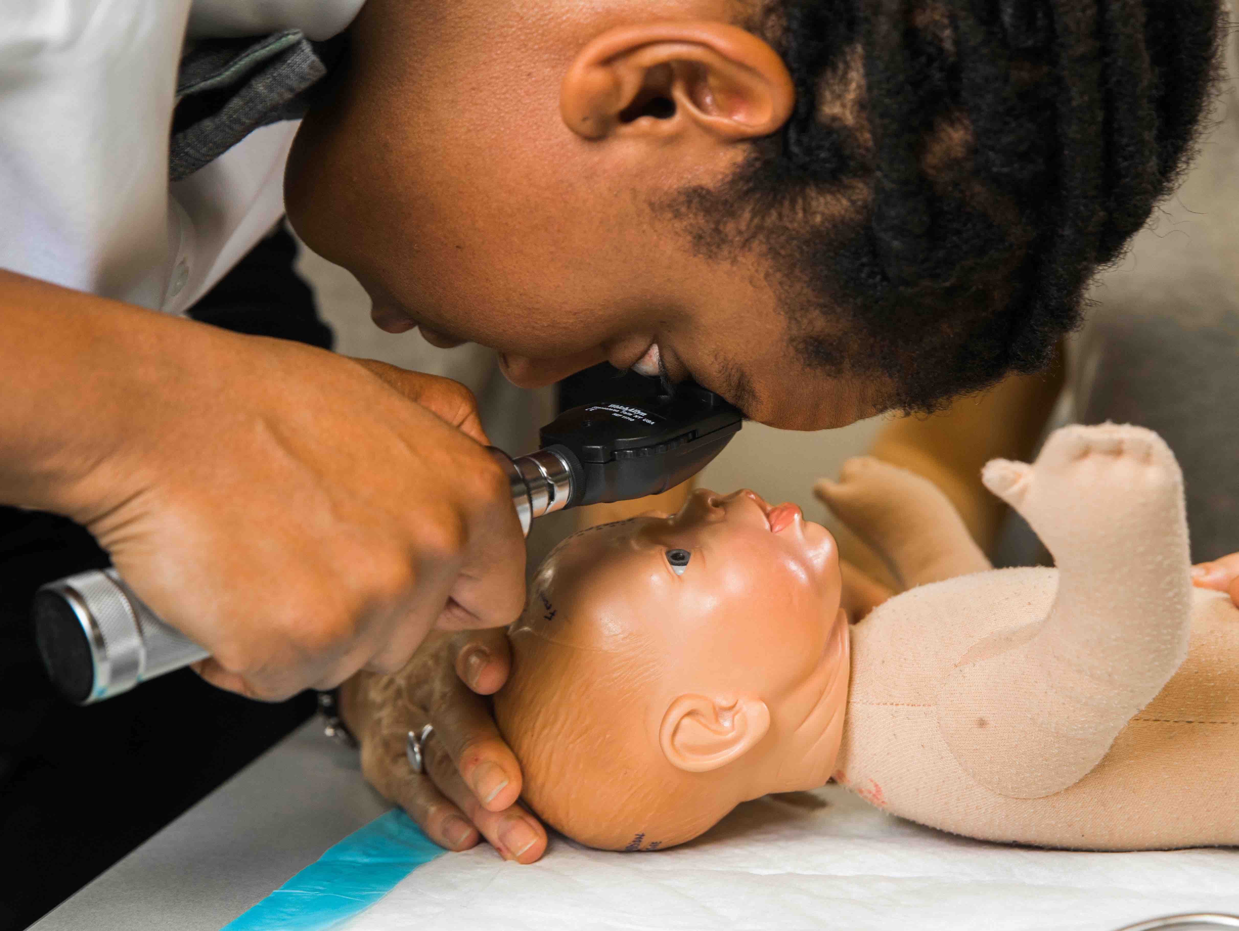 Student examining model baby with medical instrument