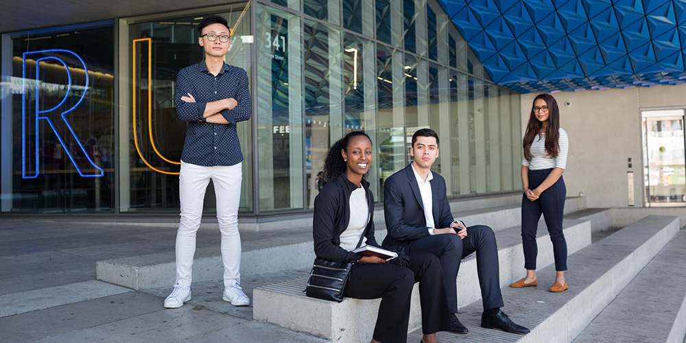 A group of four architecture and engineering students sit on the steps outside of a Ryerson building